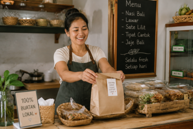 Pemilik UMKM makanan lokal sedang menyiapkan pesanan customer di warung kecil dengan suasana hangat dan produk buatan lokal Indonesia